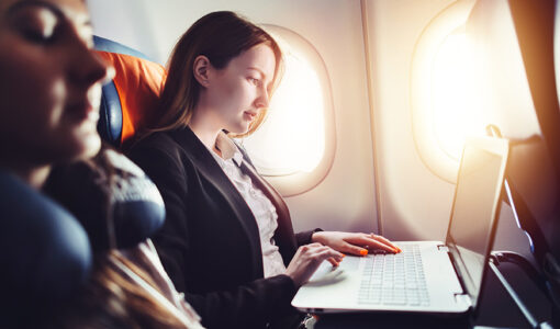 Female entrepreneur working on laptop sitting near window in an airplane